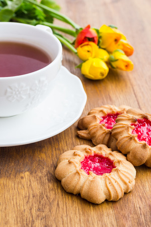 Cup of tea and biscuits with jam on a wooden tableの写真素材