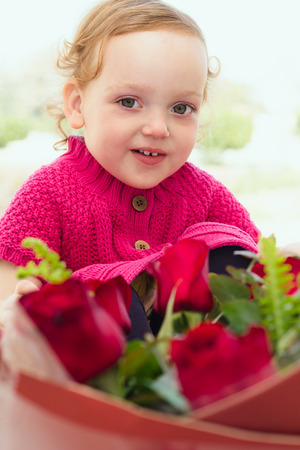 Cute little girl with a large bouquet of flowersの写真素材