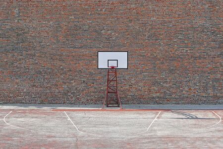 Basketball court with one hoop in front of brick wallの写真素材