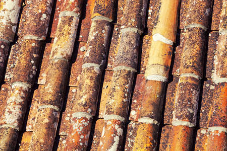 Close up of old, cylindrical red clay roof tiles on property.