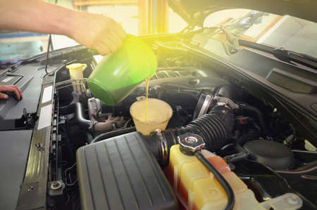 A car mechanic replacing and pouring oil at a service station.の写真素材