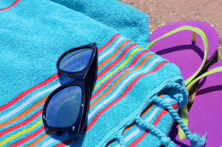 Mirrored sunglasses lie on a blue towel and the sky is reflected in them, and nearby pink beach slippers. Top view, free space. Summer holidays, vacations. Imageの写真素材