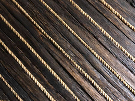 Old, worn, dark wooden boards with stripes of light ropes, wooden background texture surface.