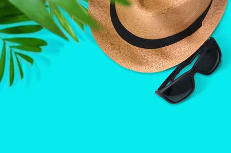 Travel vacation concept background with sunglasses, hat, camera and palm leaves on a turquoise blue background. Top view with copy space. Flat lay. Imageの写真素材