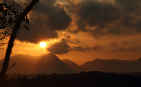bright sun in an orange sky with dark clouds at sunriseの写真素材