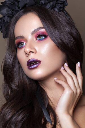 Beautiful young model with fashion make up, perfect skin, black flowers on the head. Trendy dark lips.の写真素材
