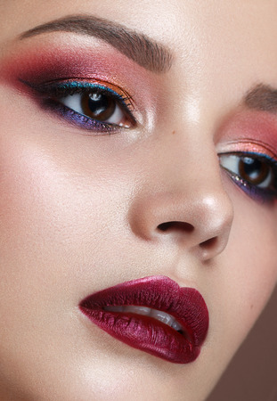 Close up portrait of beautiful young model with professional colorful makeup, perfect skin. Trendy colorful smoky eyes. Red lipsの写真素材