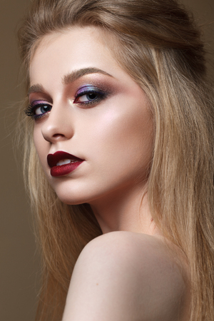 Portrait of beautiful blondy girl with professional color makeup, perfect skin. Trendy colorful smoky eyes. Evening makeup with red lipsの写真素材