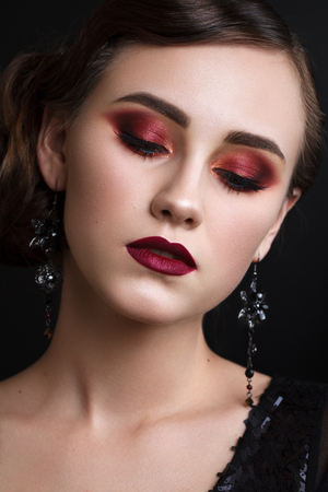 Portrait of beautiful young model with professional colorful makeup, perfect skin, red lips, retro hairdo in black clothes on dark background. Trendy colorful smoky eyes. Retro styleの写真素材