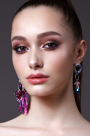 Beautiful young model with professional day makeup, perfect skin, long earringsの写真素材