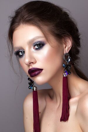 Beautiful young model with professional makeup, perfect skin, long earrings, dark lipsの写真素材