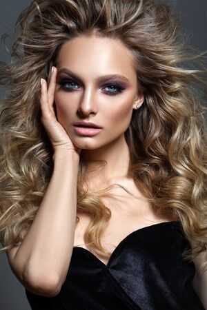 Beautiful young model with fashion make up, perfect skin, healthy hair, nude lips and fingers near the face.の写真素材