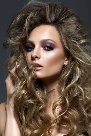 Beautiful young blond model with professional makeup, perfect skin, volume hairstyle. Colorful smoky eyes.の写真素材