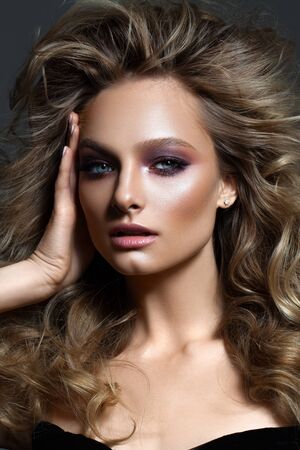 Beautiful young model closeup portrait with fashion make up, volume hairdo, nude lips and fingers near the face.の写真素材
