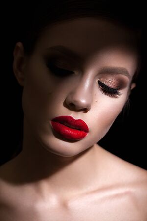 Close up portrait of a beautiful young model with bright evening make up, perfect skin and face in shadow.の写真素材
