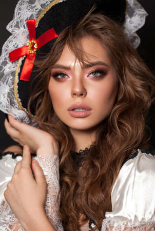 Young model with professional makeup, perfect skin, long wavy brown hair in a pirate costume. Costume party lookの写真素材