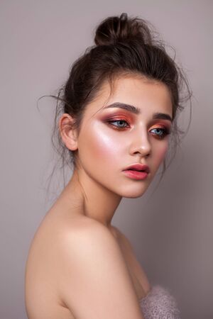 Attractive young girl with bright colorful trendy smoky eyes, blue eyes and bun hairstyle.の写真素材
