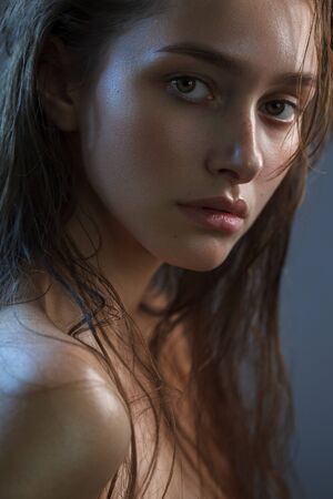 Close up portrait of an attractive model without makeup on a dark background with morning fresh look and wet hairの写真素材