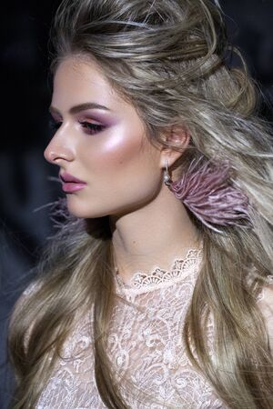 Photo of a very beautiful girl with professional lilac makeup, perfect skin and ostrich feather earrings. Wind in hair.の写真素材