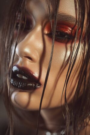 Glamour a very close up photo of a beautiful girl with glossy red smokey eyes, dark marsala lipstick, curls on the faceの写真素材