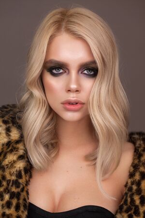 Attractive fashion model with blue eyes, blond hair, trendy smokey eyes and nude lips. Fur leopard coat.の写真素材