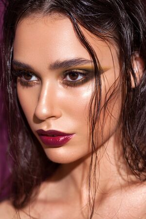 Close up portrait of a beautiful girl with trendy golden eyeshadows, rich eyebrows, marsala lipstick, wet hairdoの写真素材