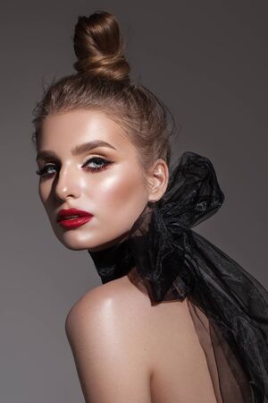 Fashion portrait of beautiful young model with professional makeup, perfect skin and black organza scarf.の写真素材