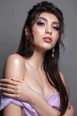 Fashion portrait of a very beautiful brunette model with professional purple makeup, perfect skin and wavy hairstyle.の写真素材