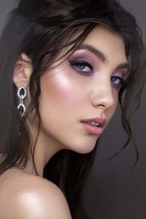 Close up portrait of a very beautiful brunette model with professional purple makeup, perfect skin and wavy hairstyle.の写真素材