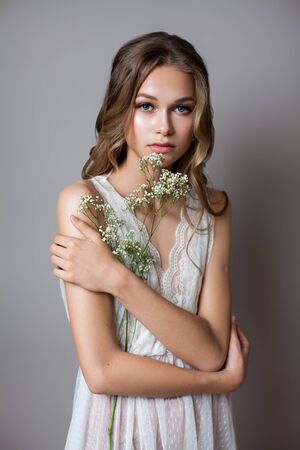 Portrait of a very beautiful young model in bridal dress with white gypsophila flowers in her hands. Romantic style.の写真素材