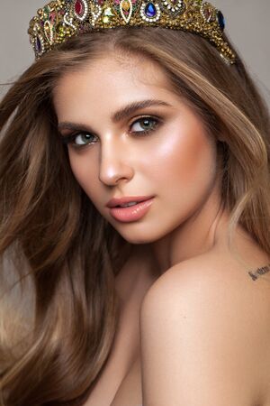 Young beautiful girl with amazing green eyes, professional makeup and crown on the head from multi-colored crystals.の写真素材