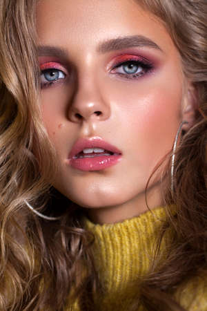 Beautiful young model with bright professional makeup, blond wavy hair, perfect skinの写真素材