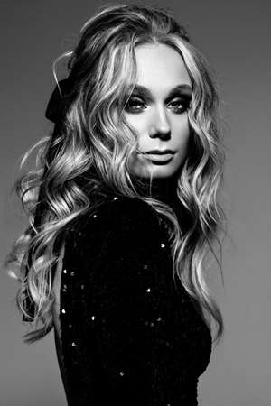 Beautiful sexy fashion model with evening professional makeup, wavy hair, perfect skin, black dress. Black and white photoの写真素材