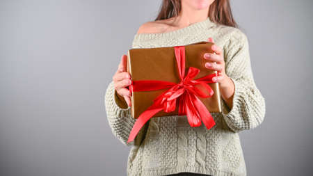 Cropped woman holds Christmas or New year decorated gift box. Copy space, isolated.