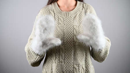 Woman in sweater and warm mittens shows her palms. Layout for new year advertising.の写真素材