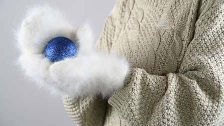 Female hands in warm mittens hold a Christmas blue ball . Winter holidays sales.の写真素材
