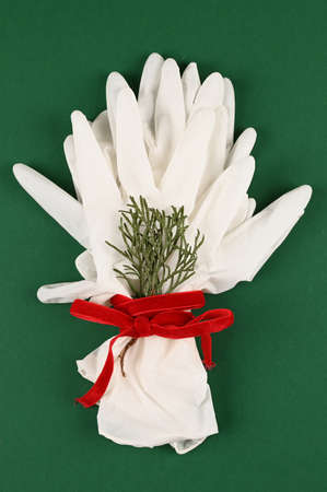Medical disposable protective gloves for hands forming a bouquet on a green background. Christmas...
