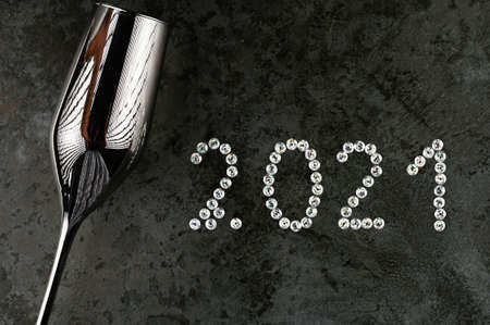 Silver wineglass and 2021 written in sparkles. New Year background.の写真素材