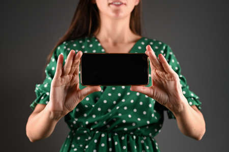 Cropped view of woman presenting smartphone with blank screen.の写真素材