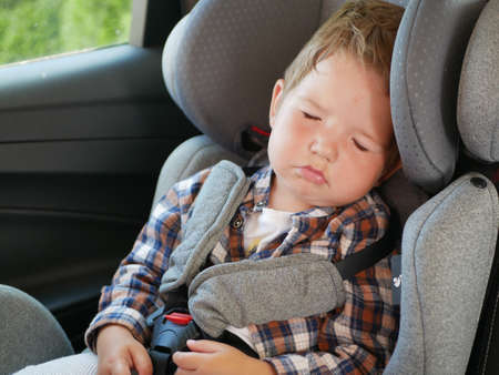 Portrait of baby boy sleeping in a car seat. Safe childhood concept.の写真素材