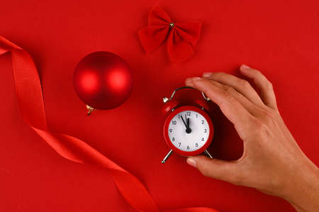 Ð¡hristmas background in red shades with alarm clock in hand, christmas ball and bow.の写真素材