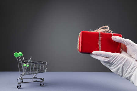 Female hands in protective gloves giving the gift box. Safety shopping form covid 19 concept.の写真素材