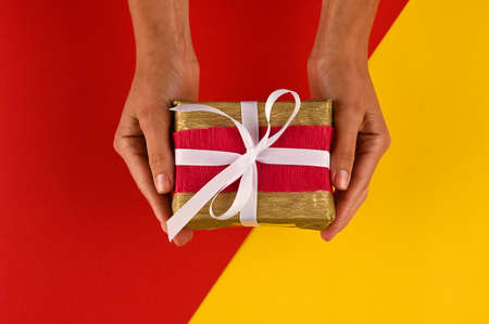 Hands holding gift in package with with ribbon and kravt paper.の写真素材
