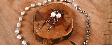 Fashionable silver earrings with pearls, necklace on wooden table. Feminine blogの写真素材