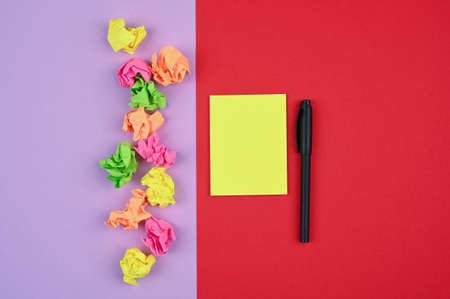 Pen and sticky notes on red-violet surface.