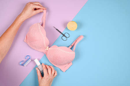 Pink bra and manicure tools on pastel blue and violet background. Female tender hands holding womans accessories. Woman beauty treatment concept, top viewの写真素材
