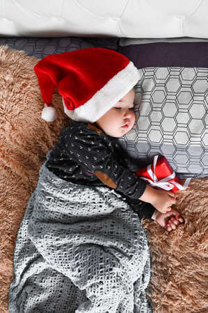 Portrait of sleeping toddler baby boy in Santa hat and gift box in his hands. Ð¡hildrens dreams and wonders conceptの写真素材