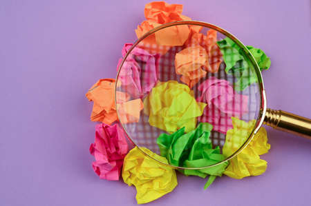 Concept with crumpled sticky notes and magnifying glass.の写真素材