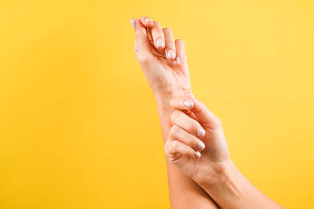 Short nails with pastel color manicure. Empty female hands on yellow background with copy space. Fashion and beauty conceptの写真素材