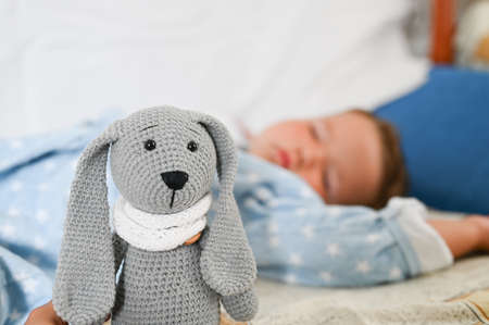 Close-up of rabbit toy against the background of a sleeping boy.の写真素材